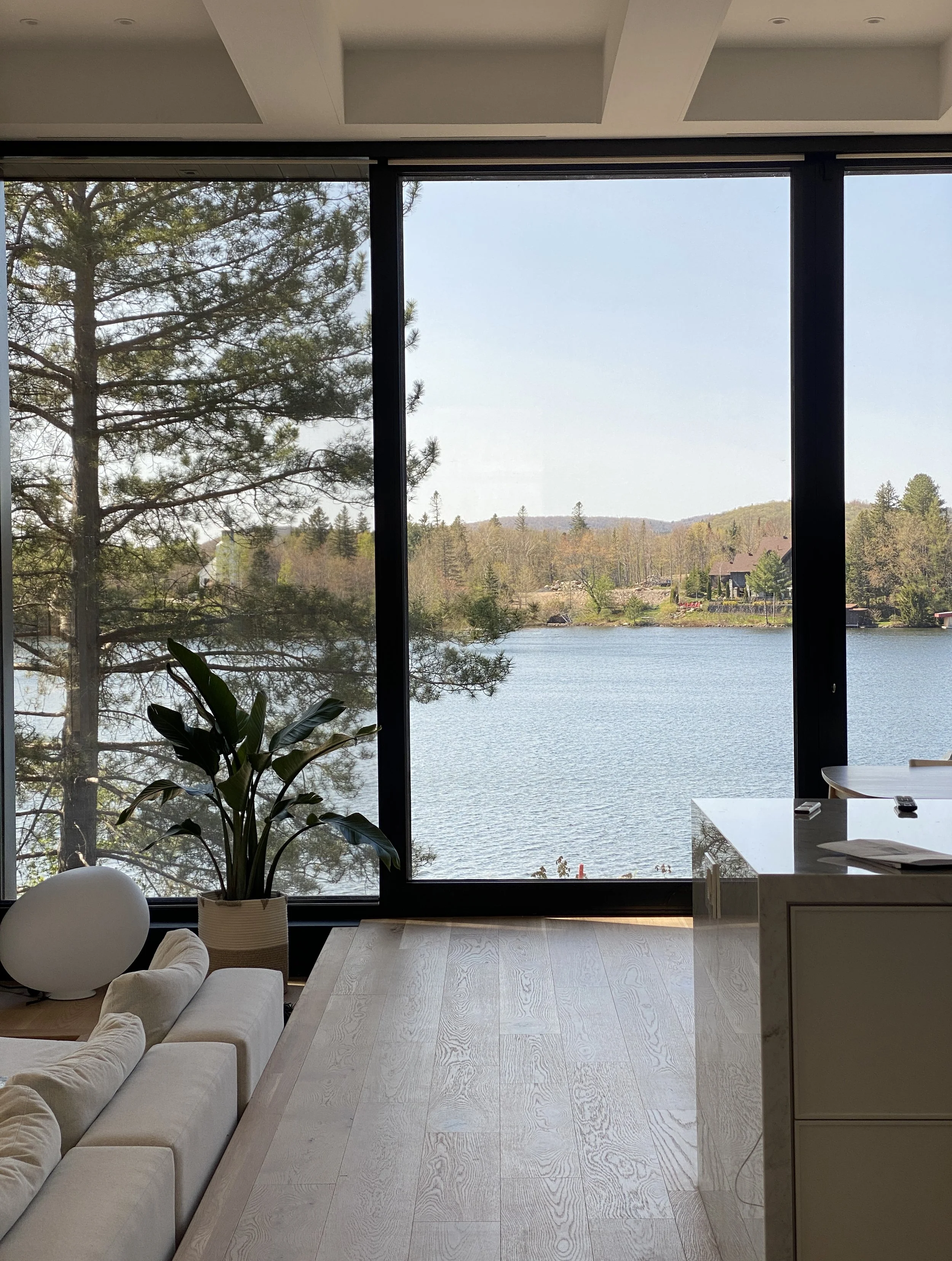 Vue depuis le salon — fenestration cadrant le lac, hauteur sous plafond de 11 pieds au rez-de-chaussée