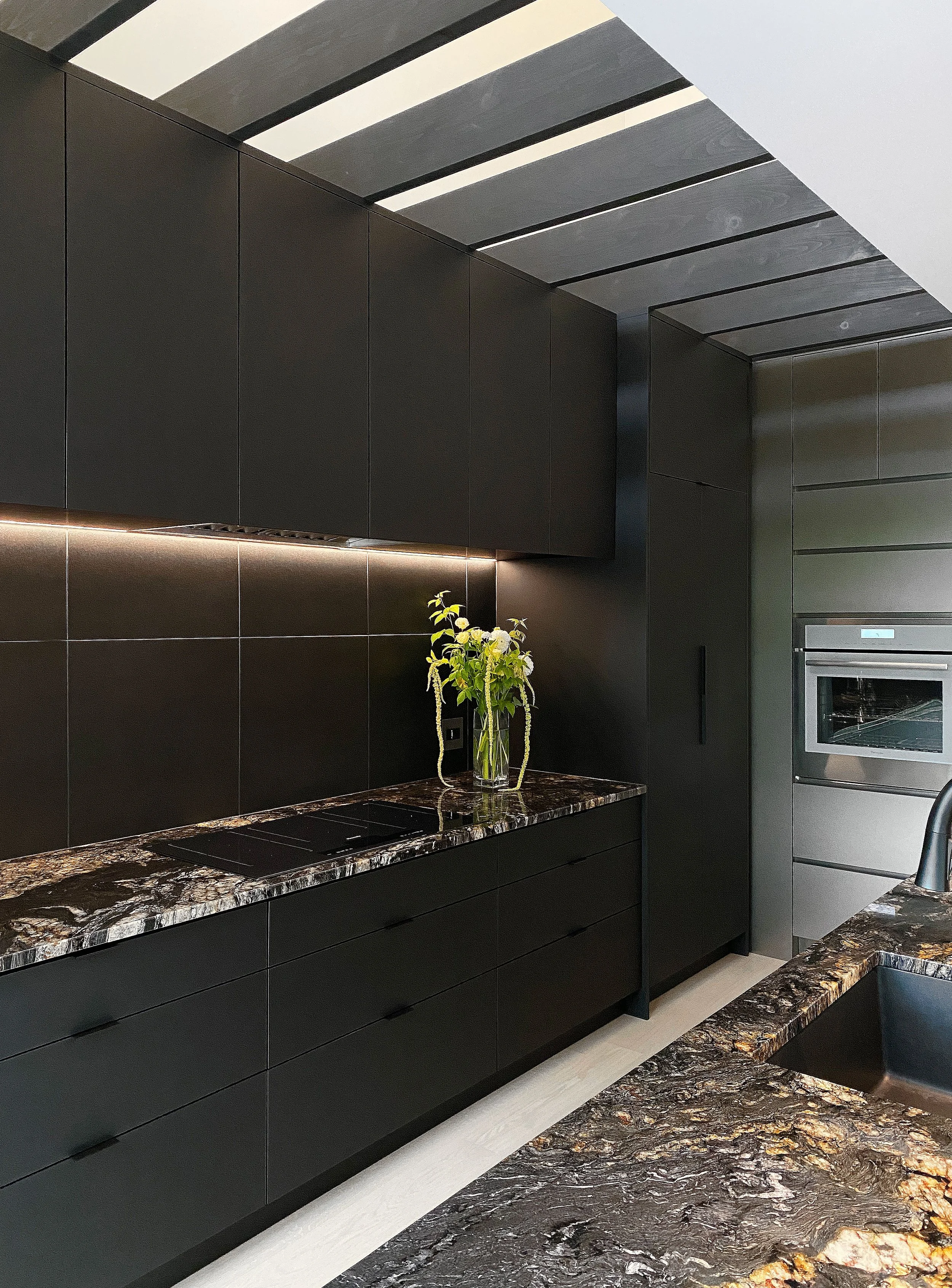 Plan de travail en granite et menuiseries de bois noir — assemblage matière à hauteur d'usage