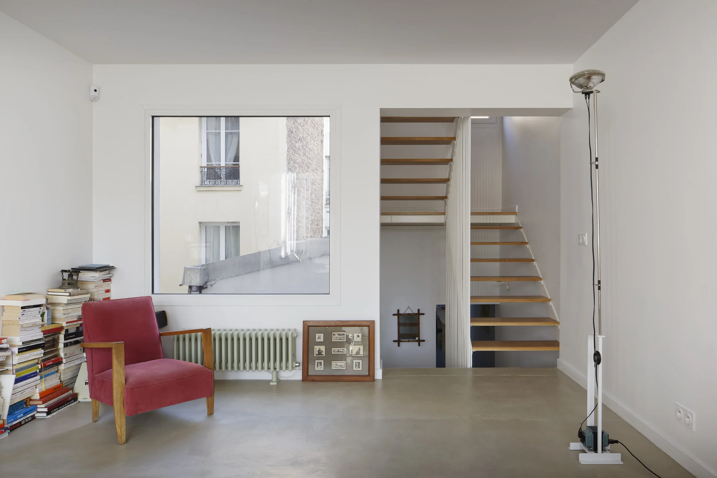 Séjour traversé par l'escalier — couture entre l'immeuble résidentiel de 4,3 m de large et le studio photographique